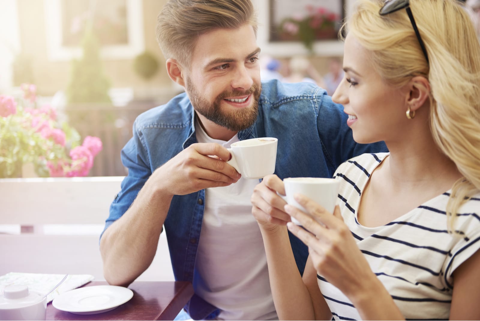 hombre con barba bebiendo café y hablando con una mujer